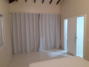 a white room with a window and a curtain at Linda casa com vista pro mar!! in Ilhabela
