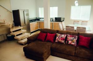 a living room with a brown couch and a kitchen at Linda casa com vista pro mar!! in Ilhabela