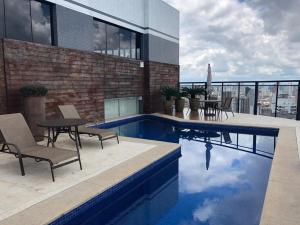a swimming pool with chairs and a table on a building at Sofisticado Loft Mobiliado no Coração do Umarizal in Belém