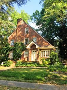 een oud bakstenen huis met een witte deur bij English Cottage in Greensboro