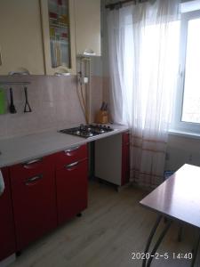 アパチートゥイにあるАпартаменты на Победы 23のキッチン(赤いキャビネット、コンロ、窓付)