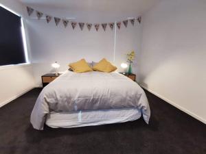 1 dormitorio blanco con 1 cama grande con almohadas amarillas en Clifden Pitstop en Eastern Bush