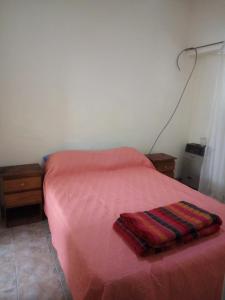 Una cama con una manta roja encima. en Departamento 4 ambientes para 5 personas 1 cama doble y una cucheta de 3 en Mar del Plata