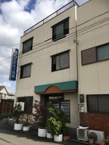 un edificio con macetas delante de él en はらビジネス旅館 en Wakayama