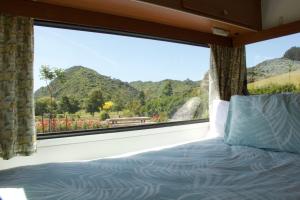a bed in a room with a large window at The Woolshed Caravans in Takaka
