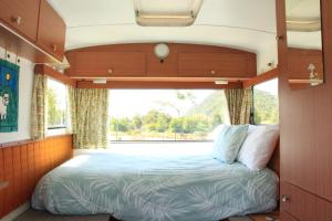 a bed in the middle of a room with a window at The Woolshed Caravans in Takaka