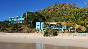 un edificio azul en una playa con palmeras en Orrie's Beach Bar and Hotel, en Crab Hill