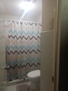 a bathroom with a toilet and a shower curtain at Your City•Home Apartment in Manila