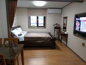 a bedroom with a bed and a flat screen tv at Sanaega Pension in Yangyang