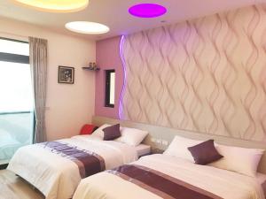 two beds in a room with purple lights on the wall at Purple Shell Homestay II in Magong