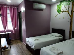 - une chambre avec 2 lits et un arbre sur le mur dans l'établissement Purple Dream Home, à Teluk Panglima Garang