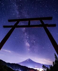 una puerta torii japonesa por la noche con una montaña en Ururun Kawaguchiko en Fujikawaguchiko