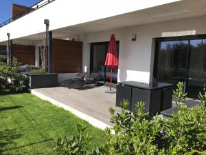 a patio with chairs and a red umbrella at Residence ACQUA LINDA Porticcio in Porticcio