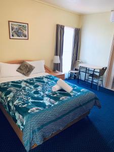 a hotel room with a bed with a blue blanket at City East Motel in Melbourne