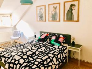 Cozy City Apartment - by Nahuen Suites في غراتس: غرفة نوم بسرير أسود وبيض وصور على الحائط