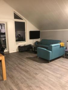a living room with a blue couch and a tv at Kjelkebakken gård 2. in Lyngseidet