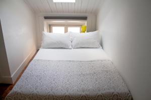 a bed in a small room with a window at WW Hostel & Suites in Coimbra