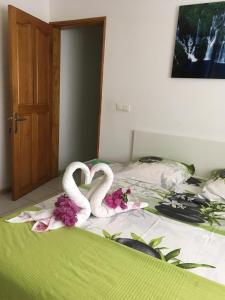 two swans are laying on a bed with flowers at Chambres d'hôtes du domaine des doudous in Saint-Pierre