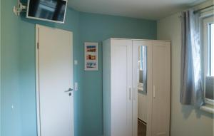 Cette chambre comprend une armoire blanche et une télévision murale. dans l'établissement 1 Bedroom Nice Apartment In Graal-mritz, à Graal-Müritz