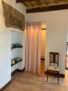 - un salon avec une chaise et un rideau dans l'établissement Casa vacanza vicolo degli orti, à Monticiano