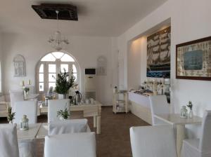 a white room with white chairs and tables and a window at Porto Scoutari Romantic Hotel in Skala