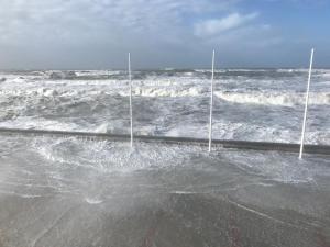 une plage avec des vagues et deux pavillons dans l'océan dans l'établissement Villa Trémail - La plage au pied de votre chambre, à Wimereux