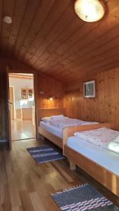 two beds in a room with wooden walls at Haus Bergfrieden in Castelrotto