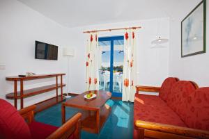 プエルト・デル・カルメンにあるAparthotel Costa Marのリビングルーム(赤いソファ、テーブル付)