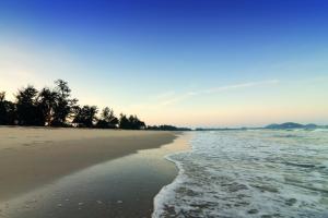 uma praia arenosa com árvores e o oceano em Pantai Regal Hotel em Kuantan