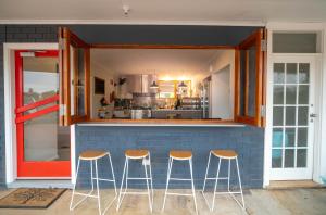 a kitchen with three stools in front of a counter at The Platypus Accommodation & Cafe in Cudal