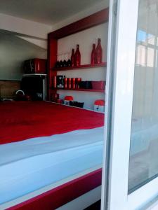 Habitación con cama con jarrones rojos en las estanterías en Le Bâbord - petit studio moderne et bien équipé à 30 m de la mer, en Palavas-les-Flots