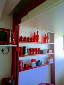 un estante lleno de jarrones de cristal rojo y un microondas en Le Bâbord - petit studio moderne et bien équipé à 30 m de la mer, en Palavas-les-Flots