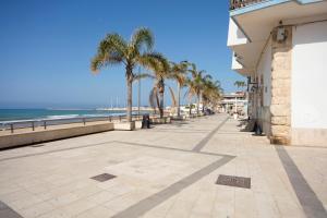 un marciapiede accanto alla spiaggia con palme di Residence Andrea Doria a Marina di Ragusa