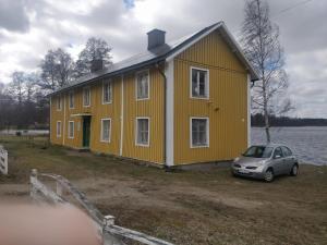 a yellow house with a car parked in front of it at Villa Gurevitch - 4 lägenheter med sängplats för två i varje lägenhet in Urshult