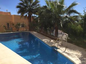 米哈斯NEW: LUXURIOUS PENTHOUSE WITH JACUZZI & SEA VIEW的一座种植了棕榈树的蓝色游泳池和一座建筑