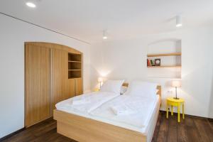 1 dormitorio con 1 cama blanca grande y armario de madera en Modern Apartment in a Picturesque 15th-Century Building, en Praga