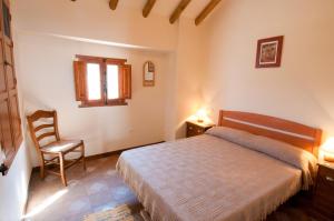 een slaapkamer met een bed, een stoel en een raam bij El Cortijo at Molino la Ratonera in Zagra