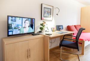 ein Schlafzimmer mit einem Schreibtisch und einem TV auf einer Kommode in der Unterkunft FewoLeipzig Süd mit Tiefgarage in Leipzig