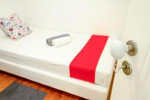 a white bed with a red and white blanket on it at Guest House Amoreiras in Lisbon