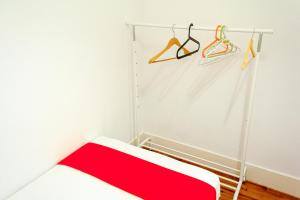 a white room with a red blanket and hangers at Guest House Amoreiras in Lisbon