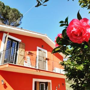 ein rotes Gebäude mit einem Balkon und einer rosa Rose in der Unterkunft B&B Il Giardino delle Camelie in Palestrina
