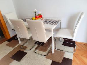 - une table et des chaises blanches avec un bol de fruits dans l'établissement Apartman Goran - 130m Radiochirurgia, à Sveta Nedjelja