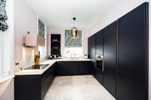 una cocina con armarios negros y fregadero en Maison Parfaite HG1 - 2 Luxury apartments with Parking Space - Near town centre, en Harrogate