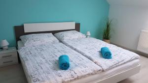 モハーチにあるPromenad Apartmanのベッド1台(上に青いスリッパ2枚付)