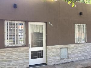a house with a white door and two windows at Ventanas al sur 2 in San Nicolás de los Arroyos
