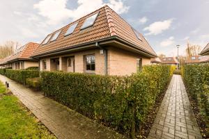 una casa con una siepe di fronte a una casa di Vakantiehuisje Walhofpark 10 a De Panne