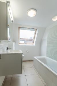 a white bathroom with a tub and a sink at Vakantiehuisje Walhofpark 10 in De Panne