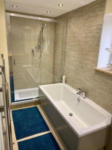 łazienka z dużą białą wanną i prysznicem w obiekcie Deri-Down Guest House w mieście Abergavenny