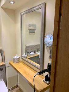 ein Bad mit einem Spiegel und einem Waschbecken im Zimmer in der Unterkunft Deri-Down Guest House in Abergavenny