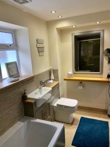 a bathroom with a tub and a toilet and a sink at Deri-Down Guest House in Abergavenny